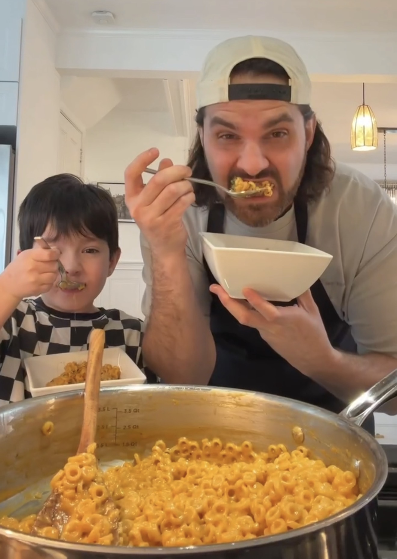 Father and son enjoying cheesy spaghettio pasta together in the kitchen