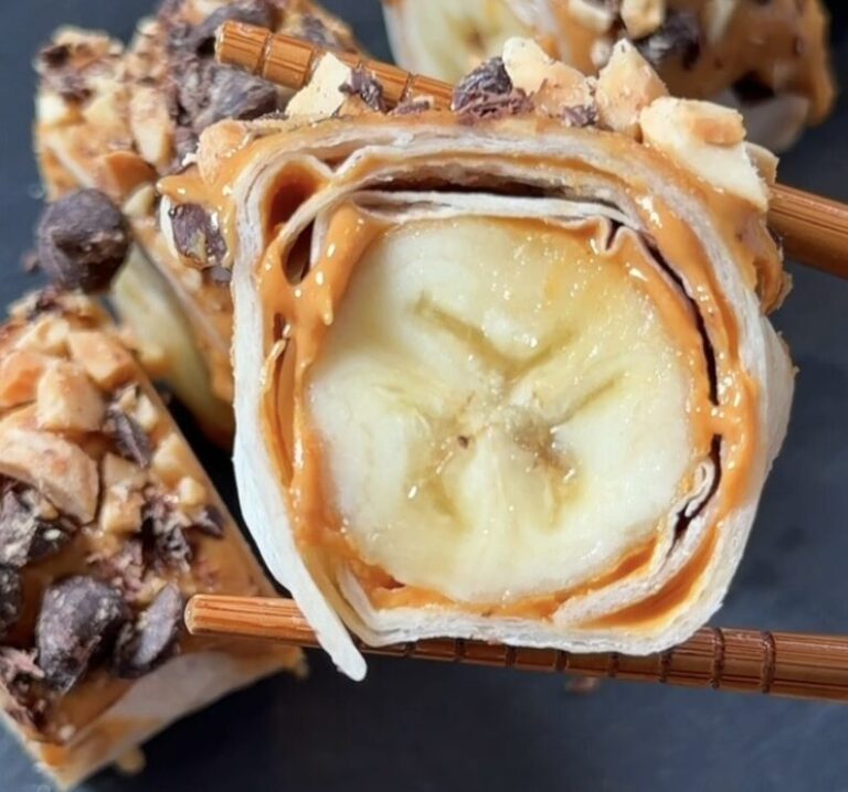 Homemade banana dessert sushi sliced into bite-sized rolls with peanut butter, chopped peanuts, and chocolate chips.
